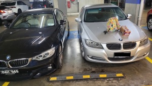 Picture of two cars squeezed into a single disability parking space